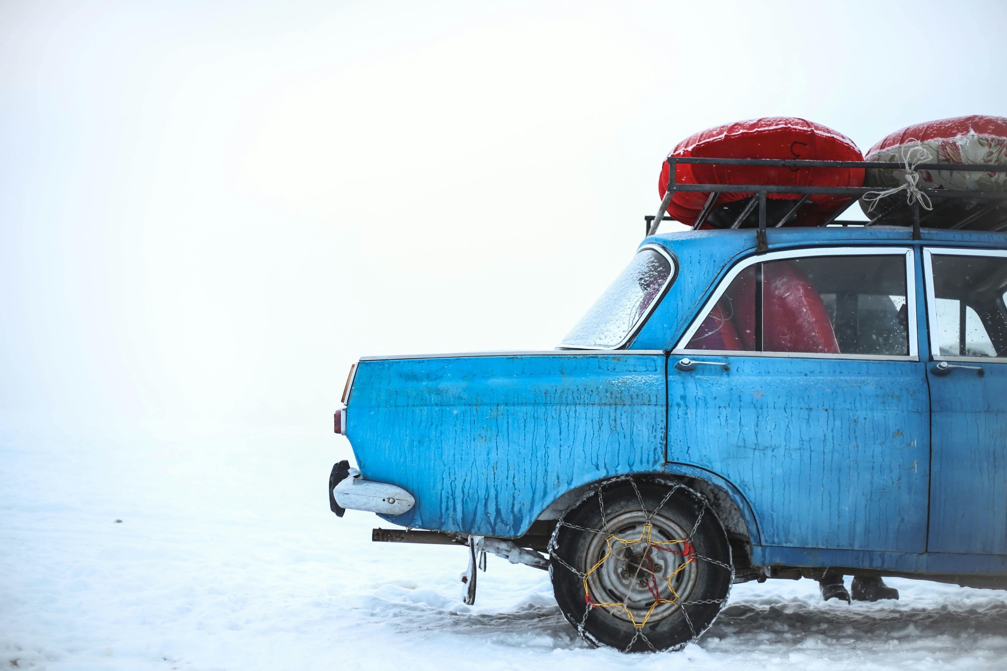 A car on a snowy road equipped with link chains, in compliance with Oregon's chain laws.