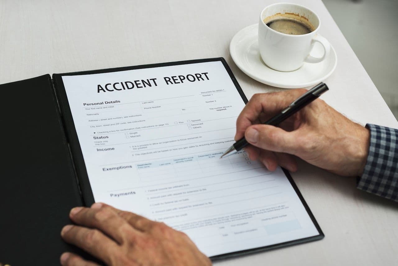 Someone filling out an Ohio accident report on the surface of a table, with a cup of coffee.