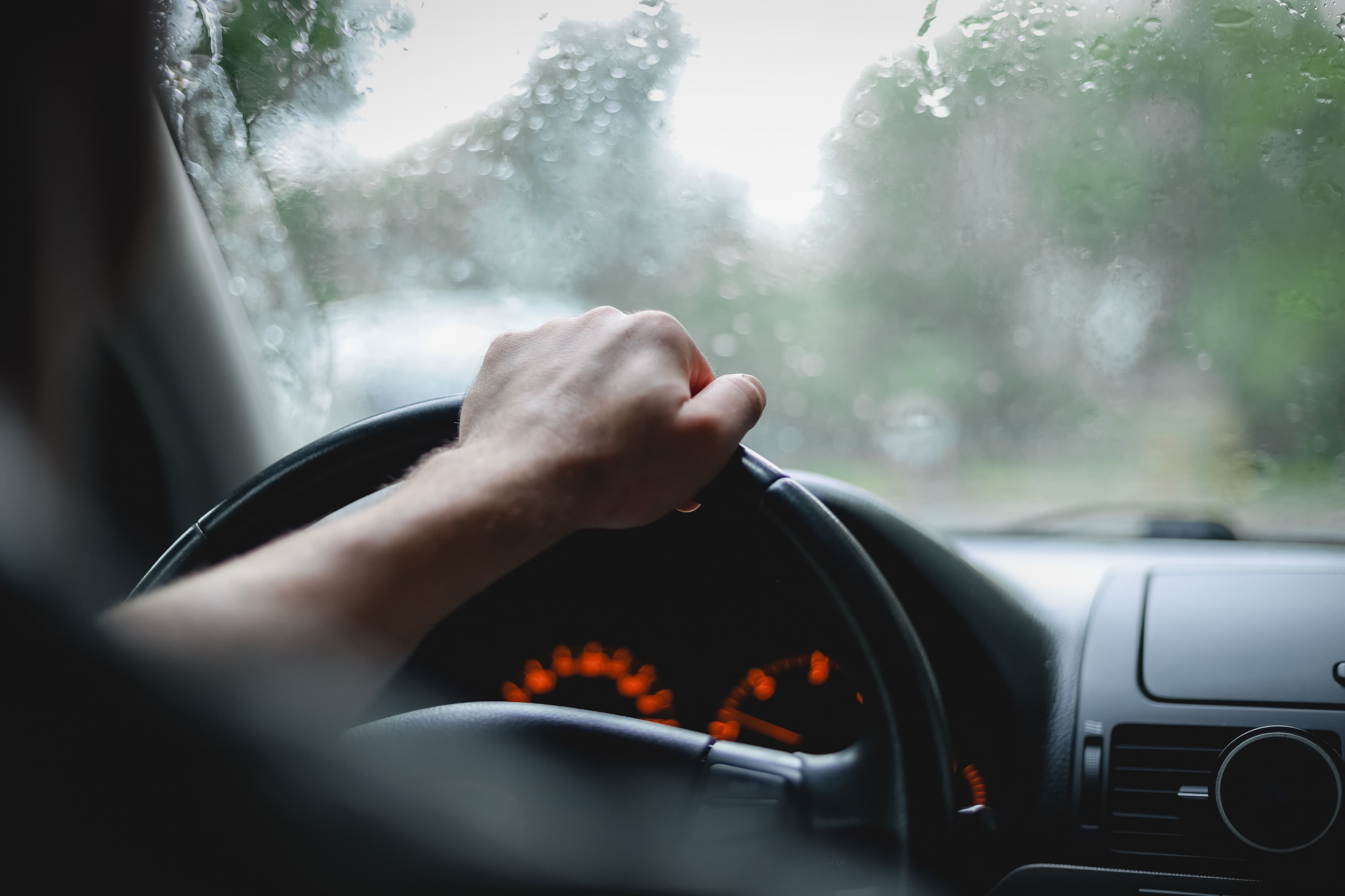 Someone driving cautiously in the rain to avoid a bad weather car accident.